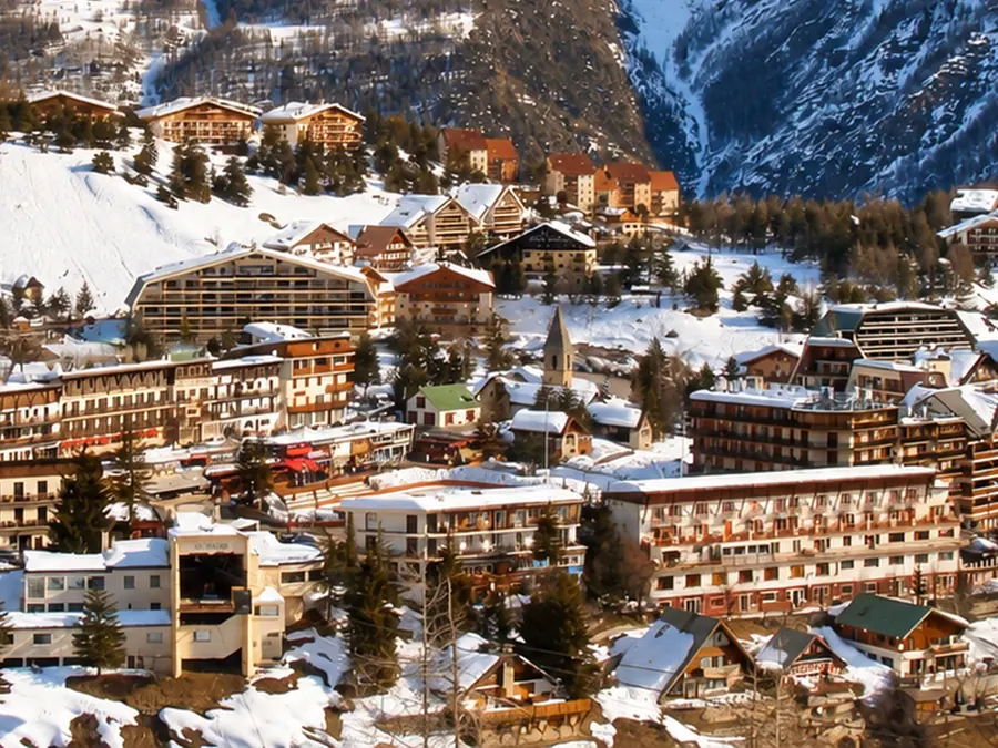 The chalets and residences of Auron under snow, among the larches