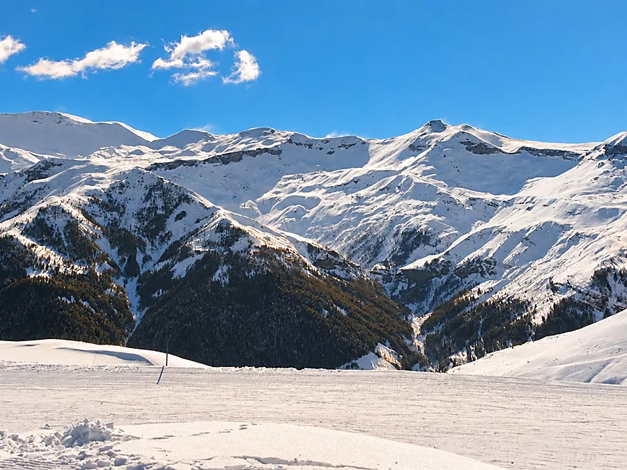 Une piste damée face aux sommets enneigés
