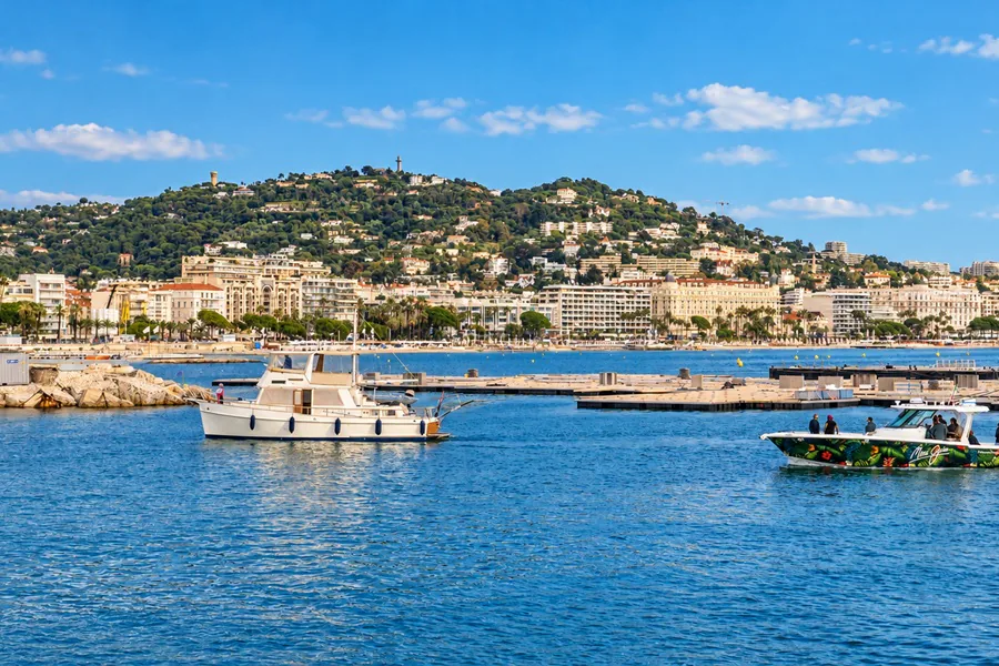 Bateaux sur la baie de Cannes, devant le front de mer et la colline couverte de maisons