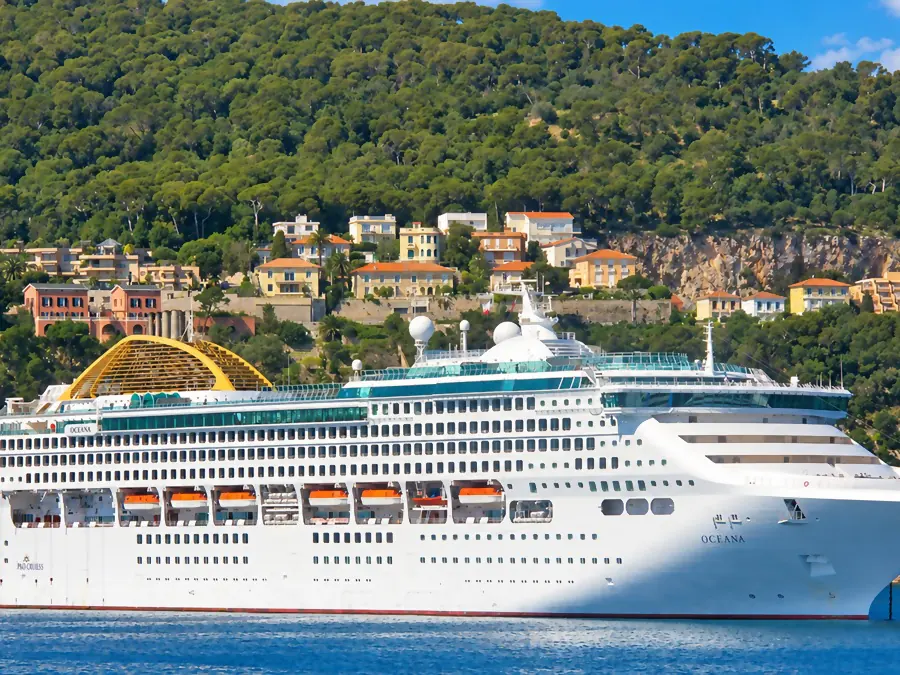 Un paquebot au mouillage dans la rade de Villefranche-sur-Mer, devant les villas et les pins de la colline