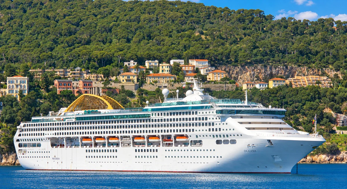 Un paquebot au mouillage dans la rade de Villefranche-sur-Mer, devant les villas et les pins de la colline