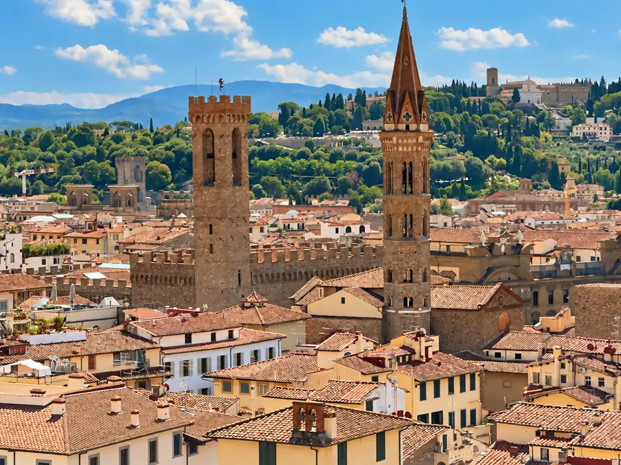 Les tours médiévales de Florence au-dessus des toits de tuiles, devant les collines toscanes