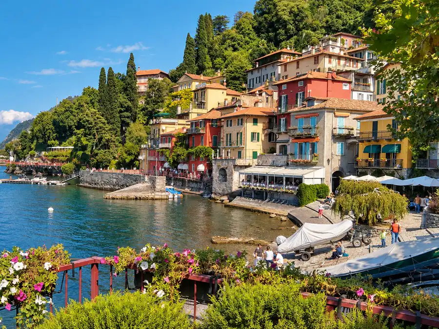 The colorful houses of a village on Lake Como, its flowered terraces and a sailboat at anchor