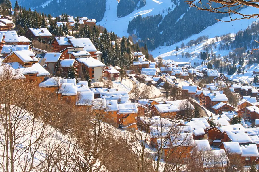 Méribel’s wooden chalets under snow on the mountainside, facing the ski runs and fir forests