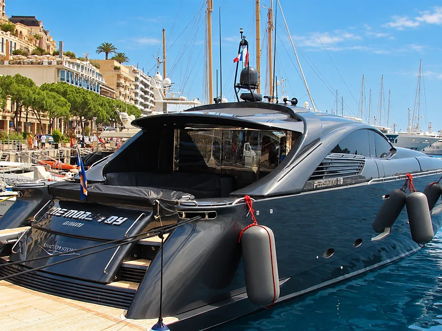 A charcoal-gray yacht moored in Port Hercules, below the buildings of Monte Carlo