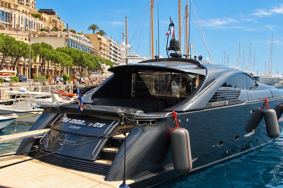 A charcoal-gray yacht moored in Port Hercules, below the buildings of Monte Carlo