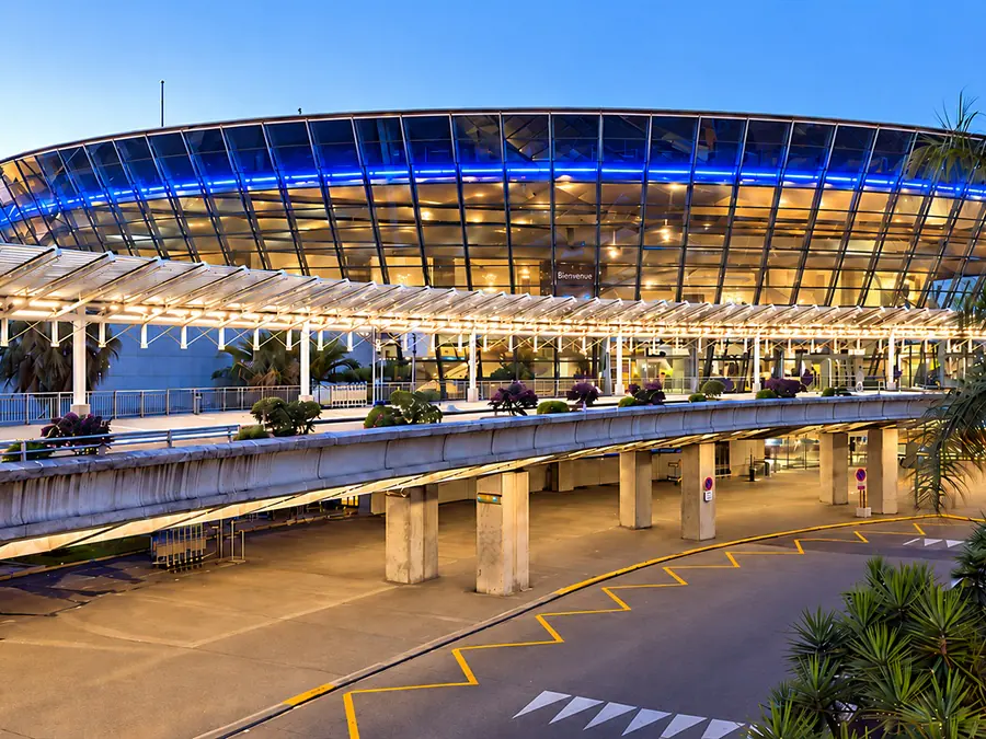 Glass terminal building of Nice Côte d’Azur Airport, framed by palm trees