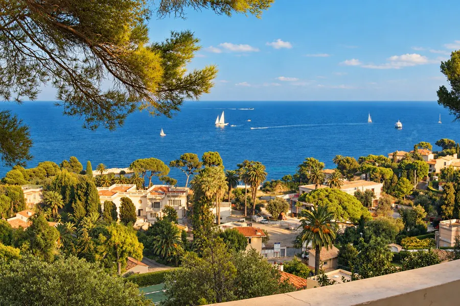 La mer et ses voiliers vus du Cap-Ferrat, entre les pins, au-dessus des maisons du bord de mer
