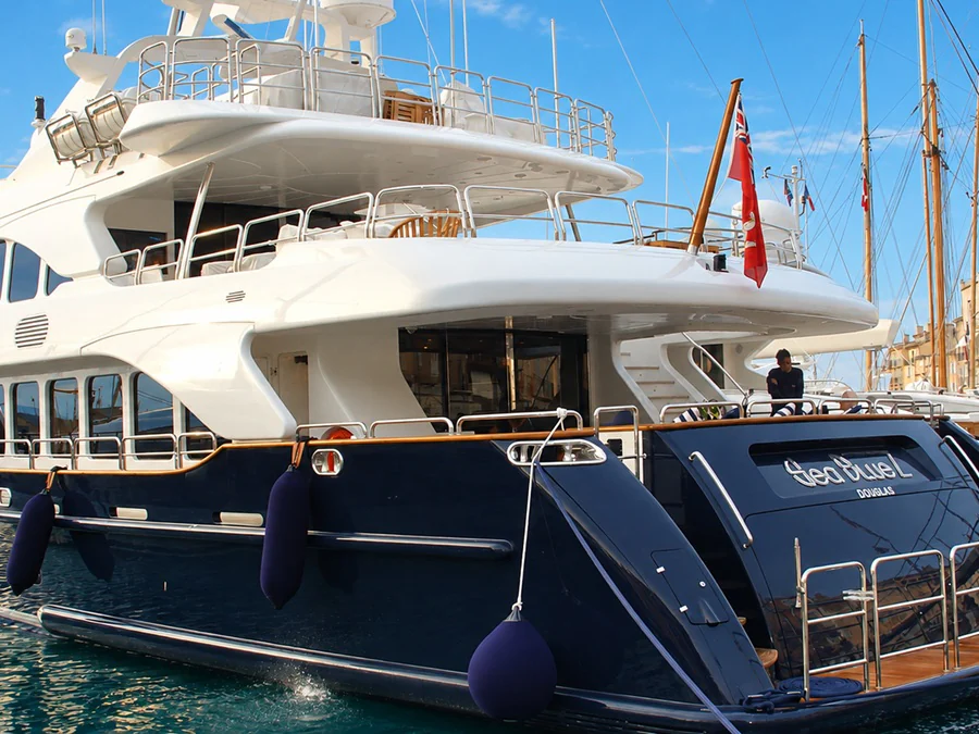 La poupe d’un yacht amarré dans le vieux port de Saint-Tropez, devant les façades colorées du quai