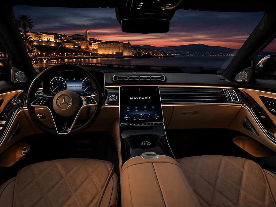 Habitacle avant d’une Mercedes-Benz, avec les lumières d’une ville de la Riviera au crépuscule derrière le pare-brise