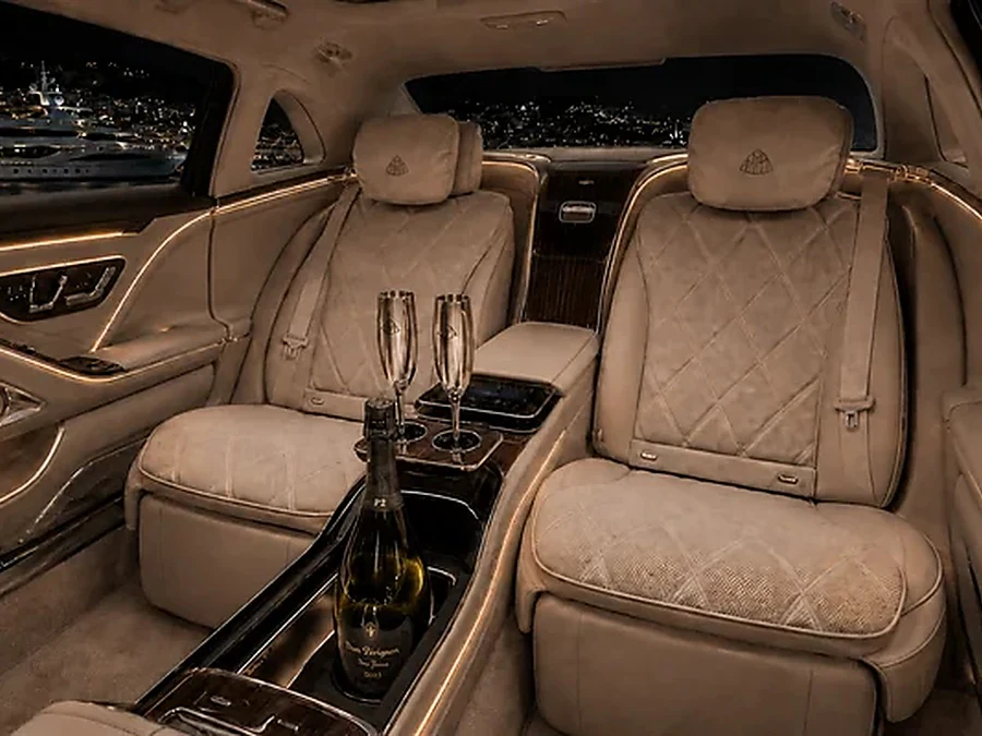 Rear cabin of a Mercedes-Maybach with two champagne flutes and a chilled bottle, ready for a private chauffeur service on the French Riviera